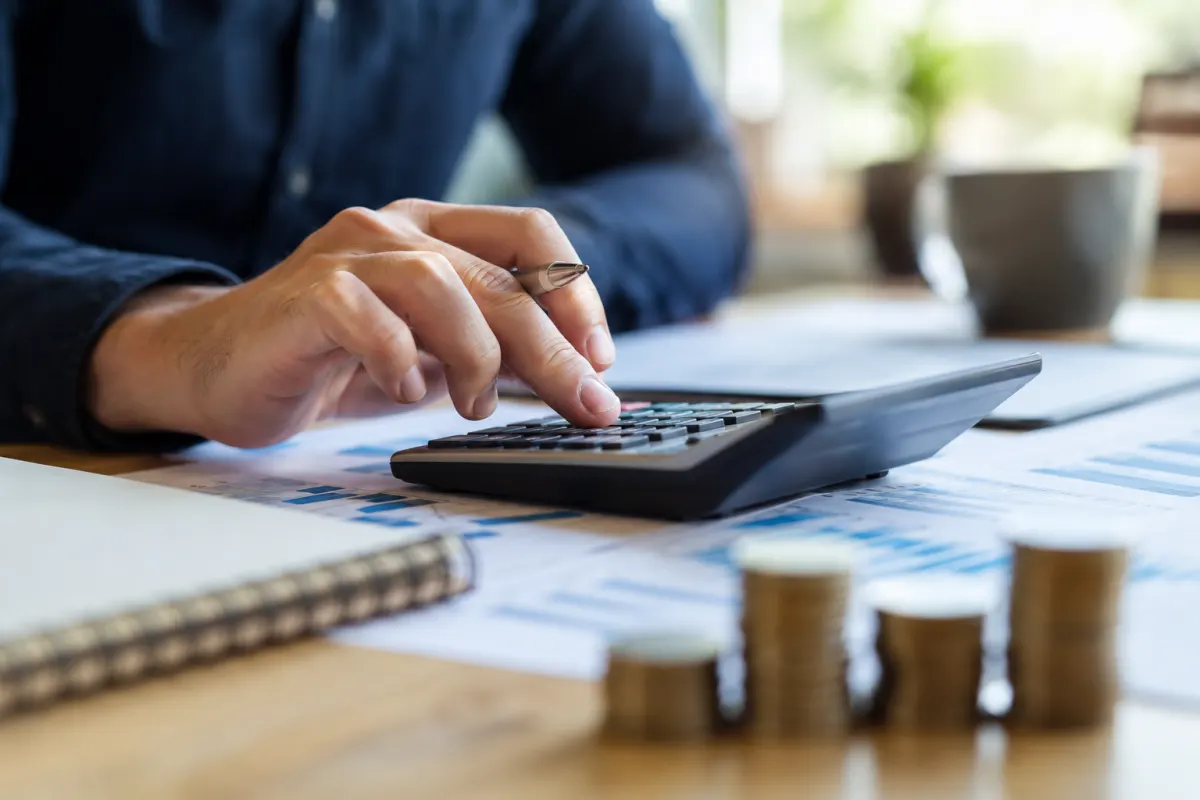 Une main de travailleur indépendant valide une ligne de calcul sur une calculatrice de bureau